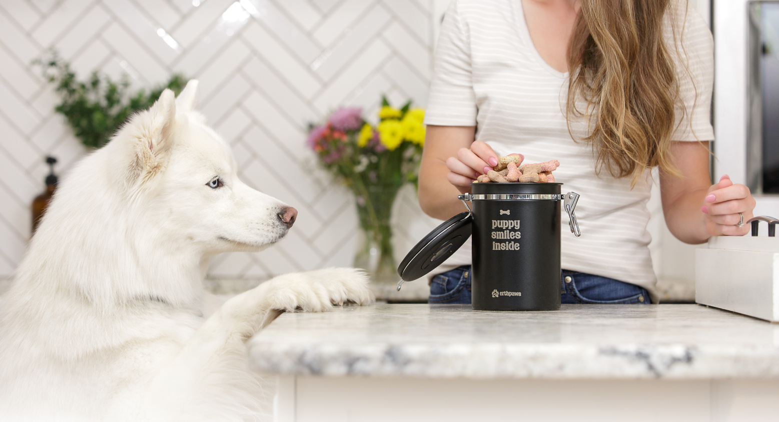 A smiling woman pouring dog treats into a Erthpaws dog treat container